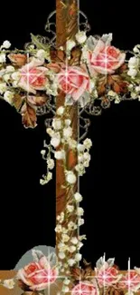 Wooden cross with pink roses and white flowers on black background.