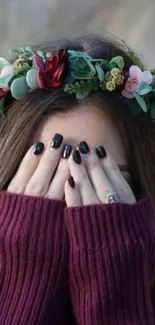 Mobile wallpaper of a woman with a floral crown hiding her face with her hands.