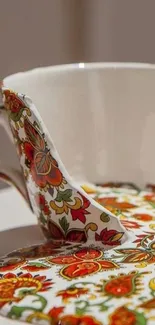 Vintage teacup with floral design and vibrant colors on a wallpaper.