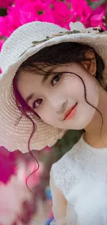 Woman with white hat surrounded by vivid pink flowers.