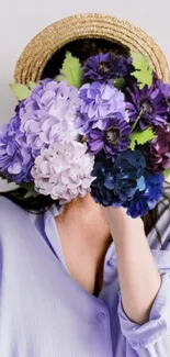 Woman with face covered by purple flowers, wearing blue shirt.