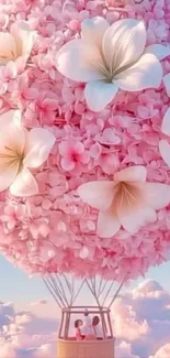Pink hot air balloon with flowers in sky.
