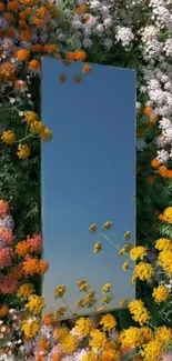 Mirror reflecting sky surrounded by colorful flowers.