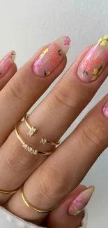 Hand with floral nails and gold rings on fingers.