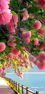 Pink flowers cascade over a lakeside path in this serene wallpaper.