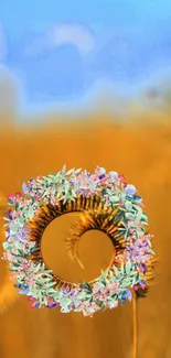 Floral ring with blue sky over golden wheat field.