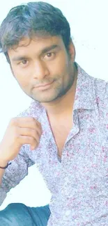 Man in floral shirt against light blue background.