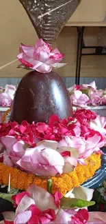 Mobile wallpaper featuring a Shiva Linga decorated with pink flowers.