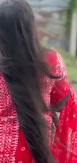 Woman with long hair in a red dress walking outdoors.