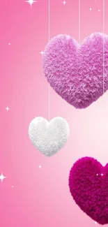 Fluffy hearts hanging against a pink background