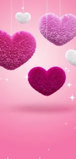 Pink wallpaper with fluffy hearts hanging.