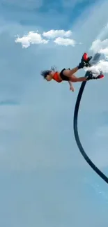 Person flyboarding against cloudy sky, performing an aerial flip.