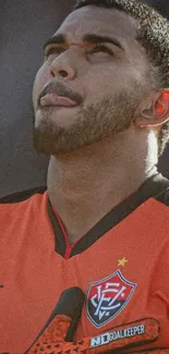 Portrait of a football player in an orange jersey, looking focused.