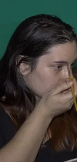 Person applying makeup with a brush, focusing intently.