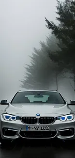 Sleek car driving on foggy road with illuminated headlights.