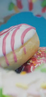 Colorful donuts with pink frosting and sprinkles against cyan blue background.