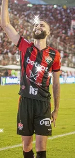 Football player celebrating a victory on the field with fans in the background.