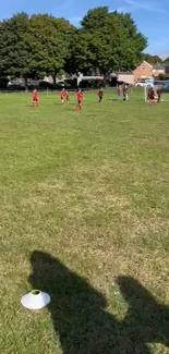 Soccer players on bright green field under a blue sky in a neighborhood park.