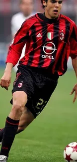 Football player in red and black jersey dribbling during a match.