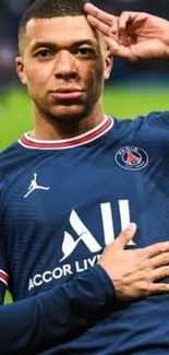 Football star in blue jersey salutes on field background.