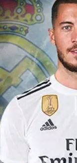 Football player in white jersey with club emblem background.