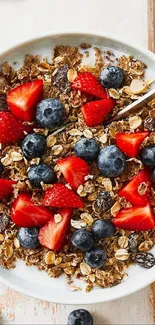 Bowl of granola with fresh strawberries and blueberries on white table.