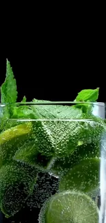 Glass of mint and lime with soda water on black background.