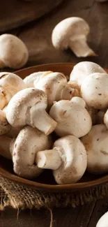 A bowl of fresh white mushrooms on a rustic wooden surface.