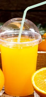 Refreshing orange juice in a clear cup with ripe oranges.