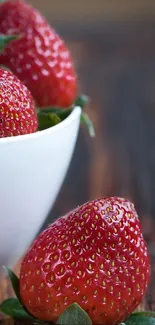 Fresh strawberries in a bowl on a rustic wooden table, perfect for mobile wallpaper.