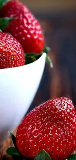 Fresh red strawberries in white bowl on wooden table wallpaper.