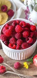 Vibrant red raspberries in a bowl with apples and flowers on a rustic table.