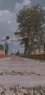 Friends balancing on train tracks under a clear sky and trees.