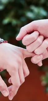 Two hands with bracelets interlocked, symbolizing friendship.