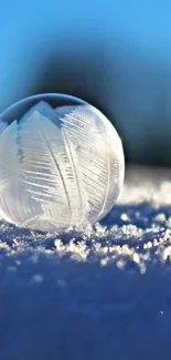 Frozen bubble rests on snow under blue sky.