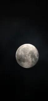 A full moon shining prominently against a dark, starless night sky.