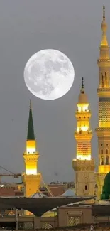 Full moon over mosque towers with a gray night sky backdrop.