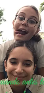 Two girls having fun outdoors with green background.