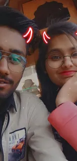 Playful selfie of two friends with red horn filter.