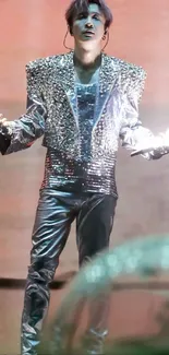 Performer in shiny silver outfit on vibrant stage.