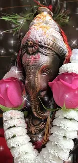 Ganesh idol with pink flowers and garland in a spiritual setting.