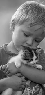 Monochrome image of child gently cradling a kitten.