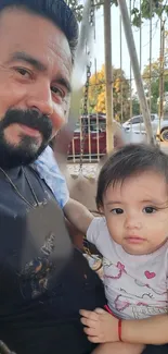 Father and child enjoying a day at the park on a swing.