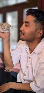 Man holding a small puppy in a cozy room setting.