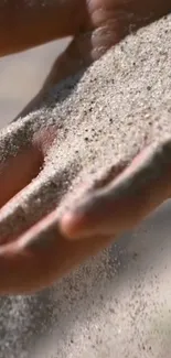 Hand gently letting sand flow through fingers, capturing a serene moment.