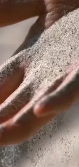 Calm scene of sand gently flowing through a hand with soft lighting.