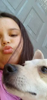 Girl taking a selfie with a cute dog in front of a gray background.