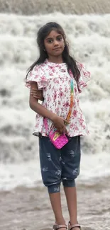 Young girl standing before a waterfall.