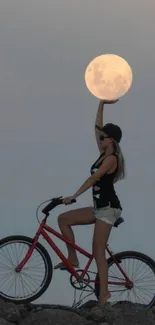 Girl on bike reaching for moon on rocky terrain, serene scene.