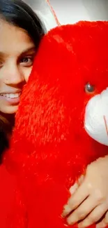 Mobile wallpaper of girl hugging a large red teddy bear with a big smile.